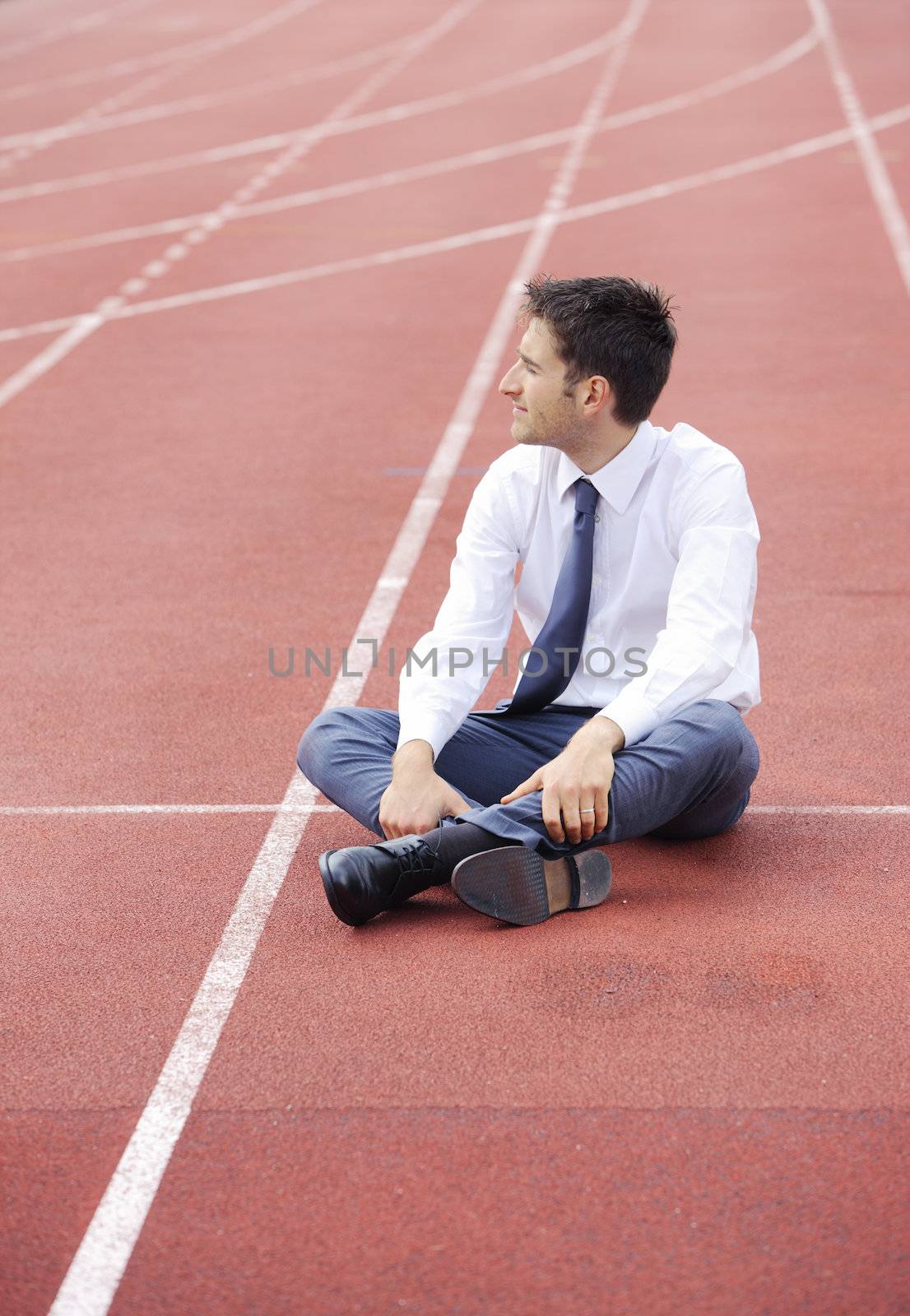 A businessman is sitting on the sports track, conceptual image