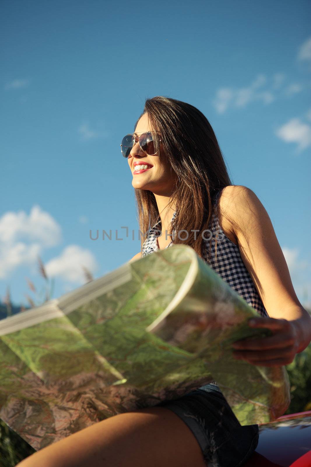 Young beautiful woman wearing sunglasses holding a roadmap