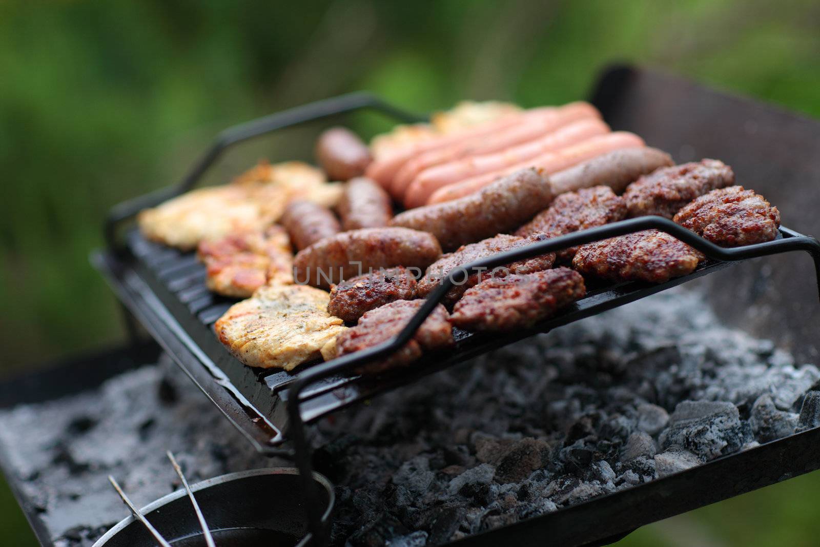 Grilling at summer weekend. Fresh meat preparing on grill. Shallow deep of field