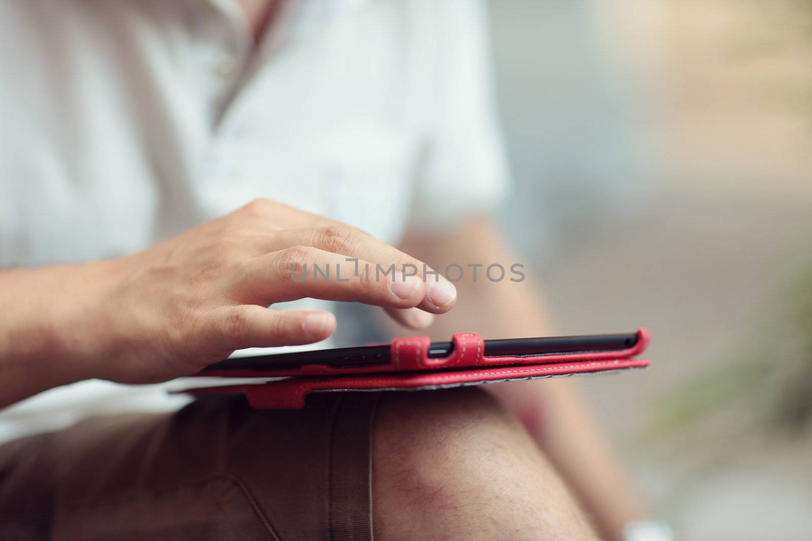 Young man using a digital tablet, hands close up. Shallow deep of field