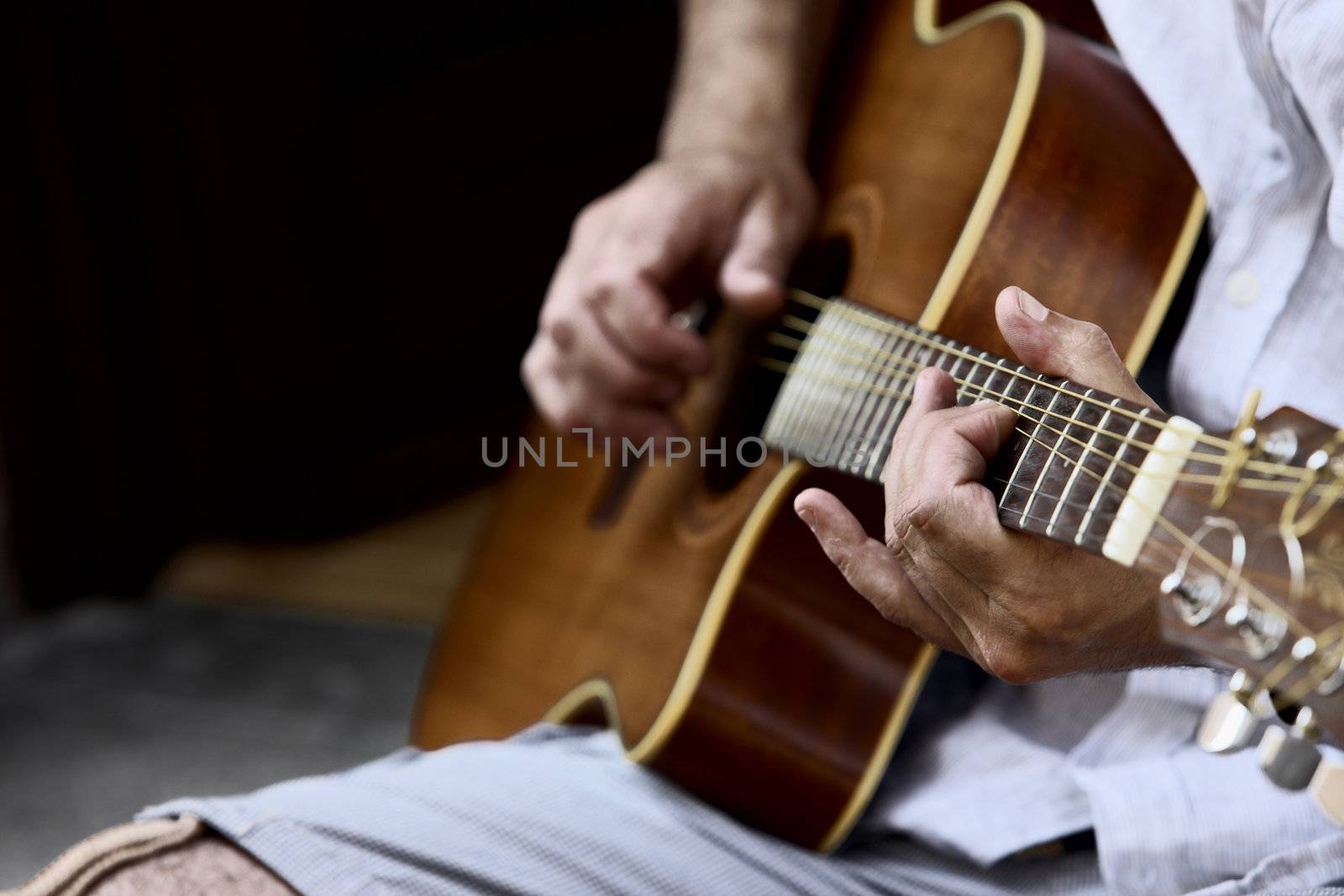 Closeup of acoustic guitar and the musician hands, shallow deep of field