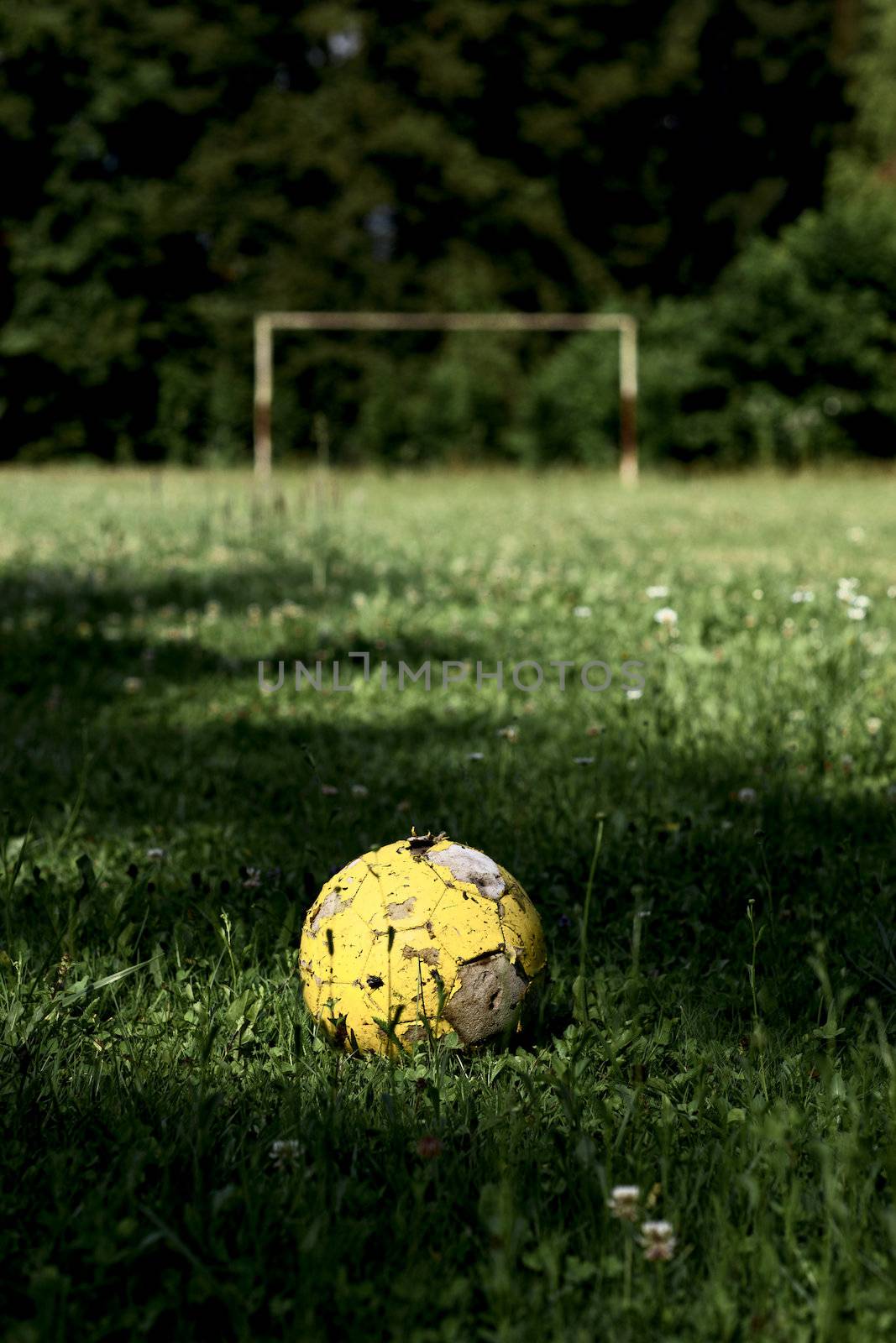 Old yellow ball on soccer field 