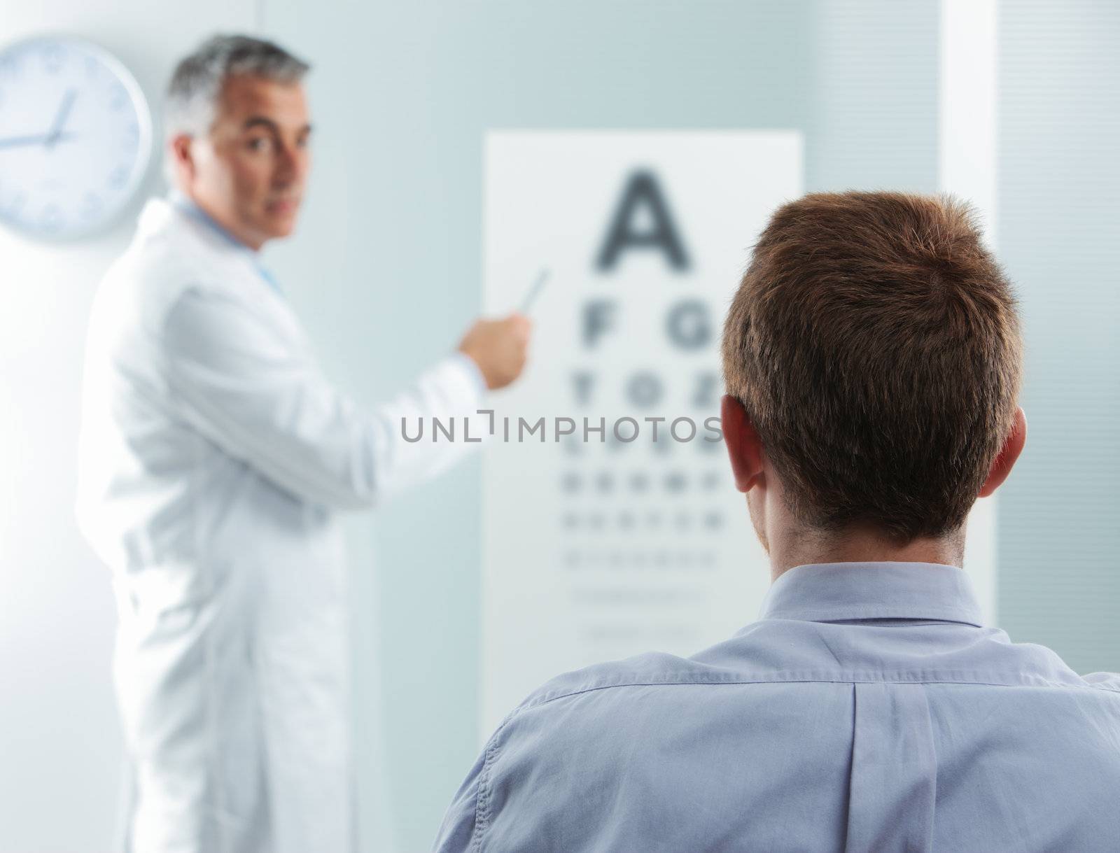 Optometrist and patient, doctor pointing at eye chart 