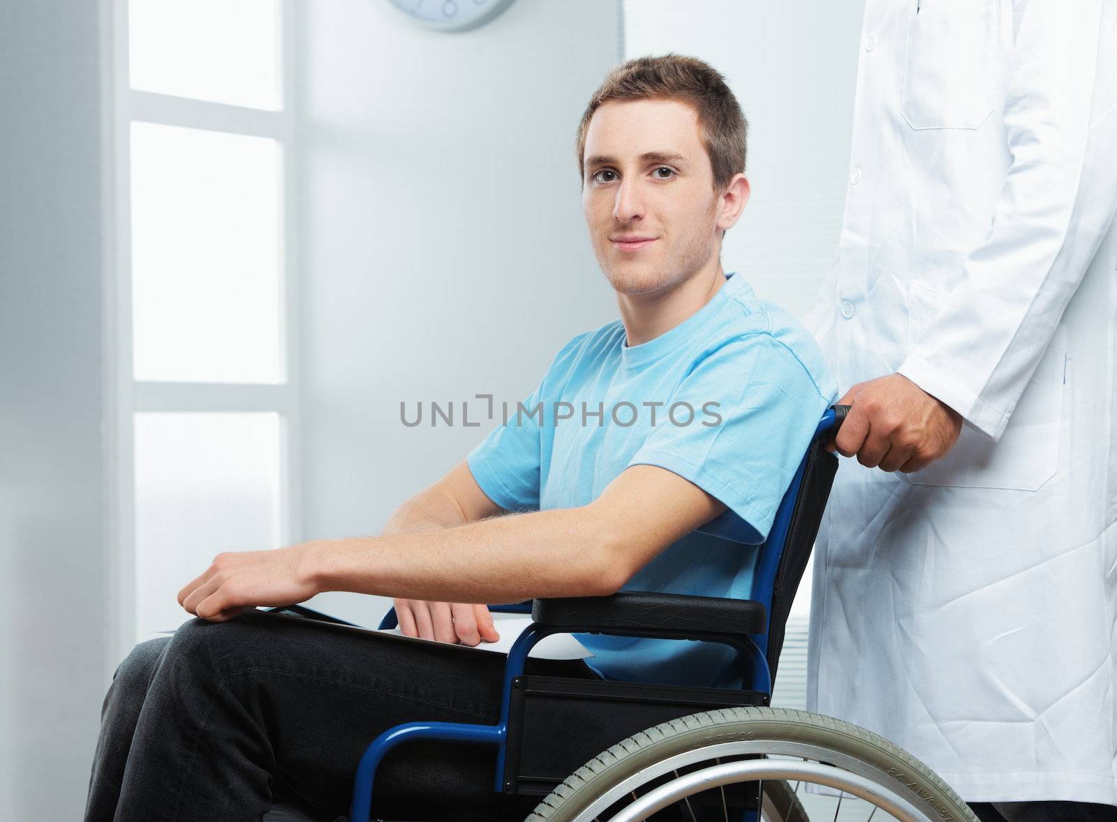 Male nurse pushing her patient on a wheelchair by stokkete