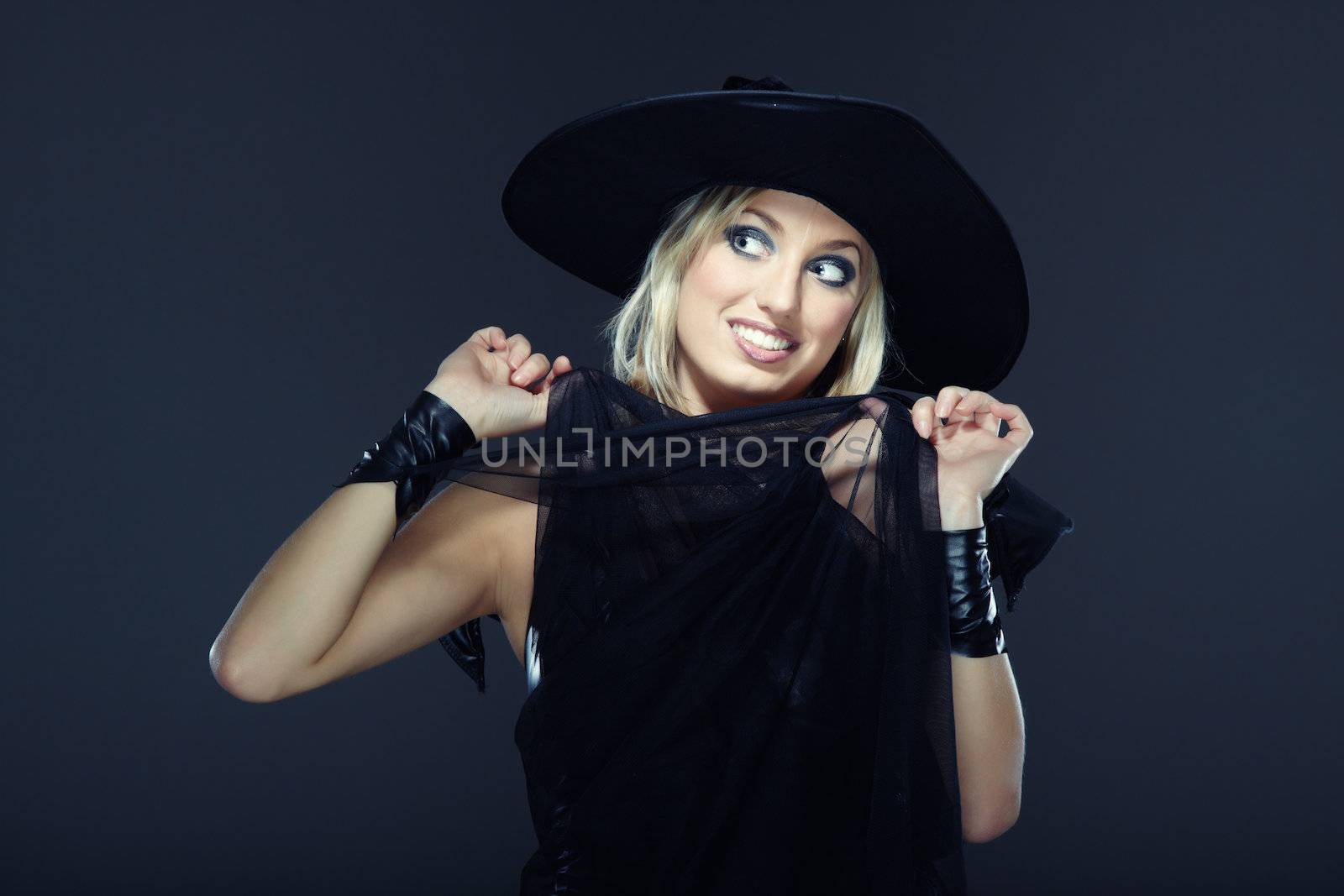 Smiling lady in the Halloween witch costume on a dark background