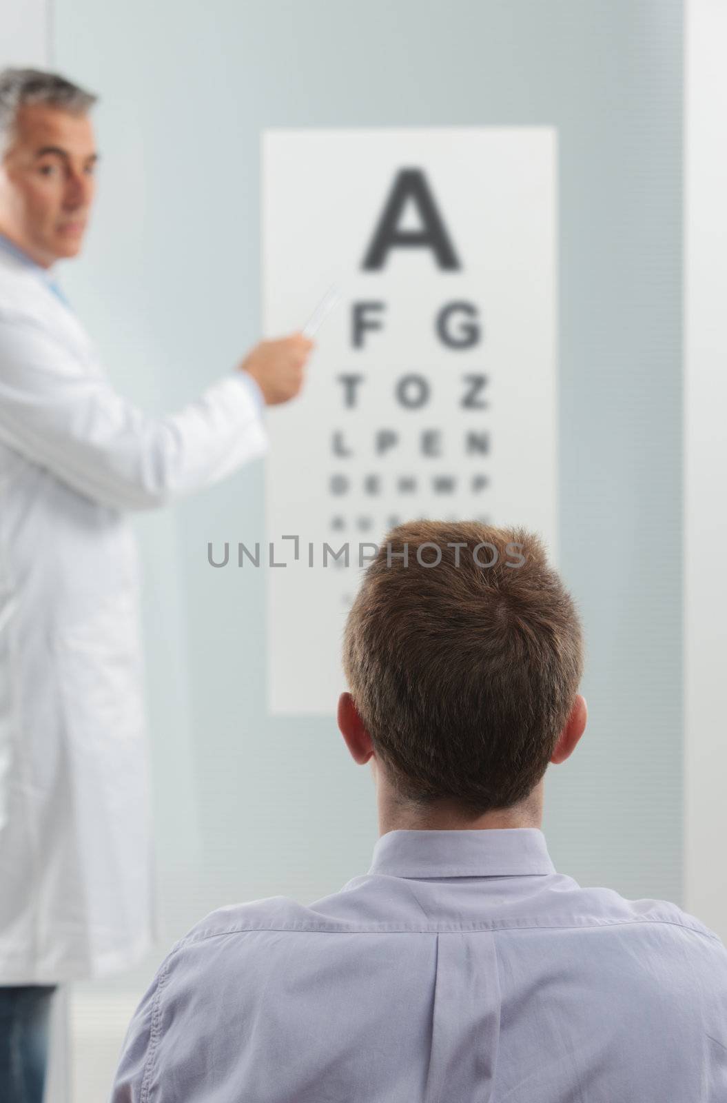 Optometrist and patient, doctor pointing at eye chart 