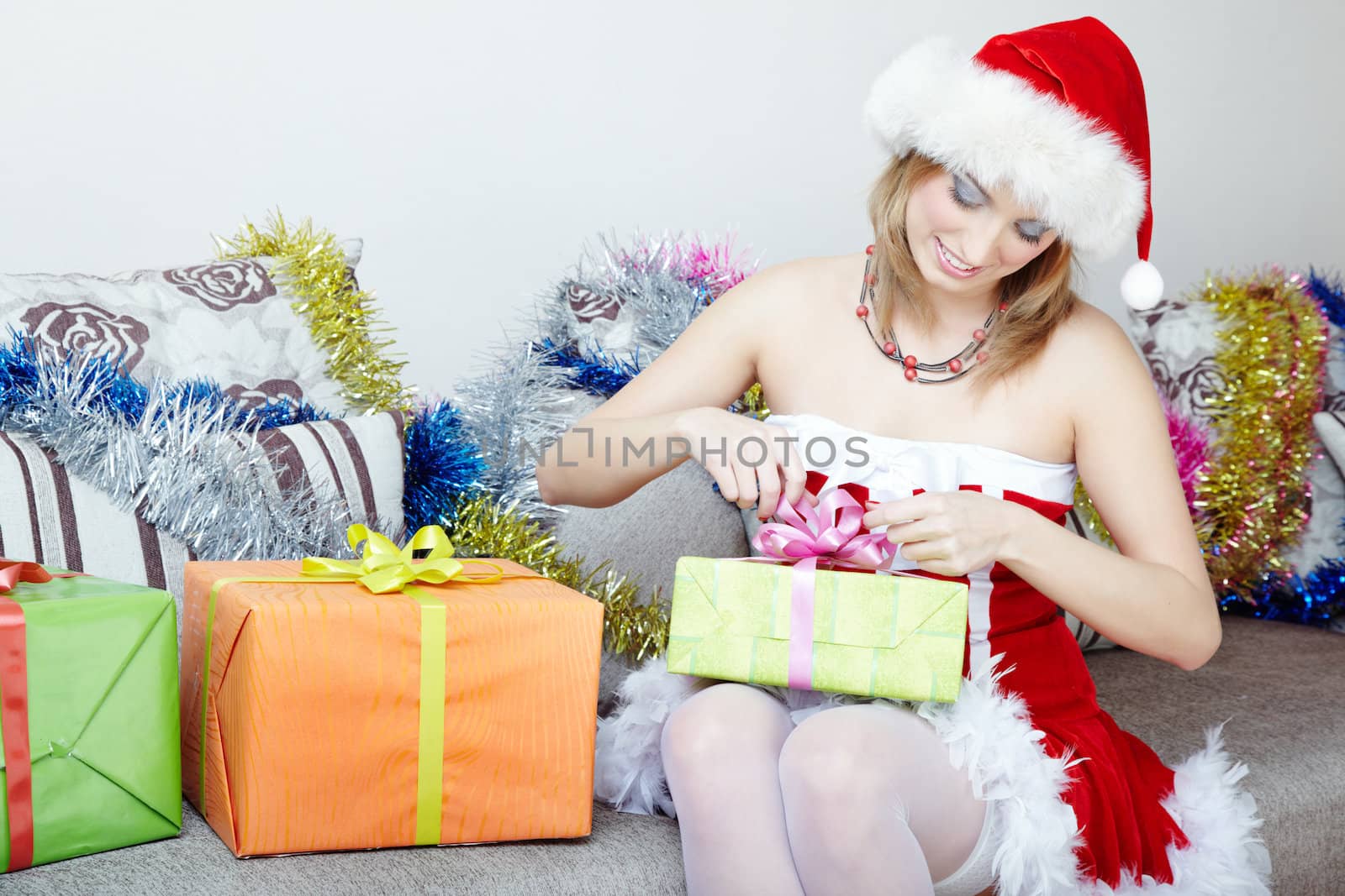 Smiling lady in the red furry Santa Claus costume and hat holding Christmas gifts