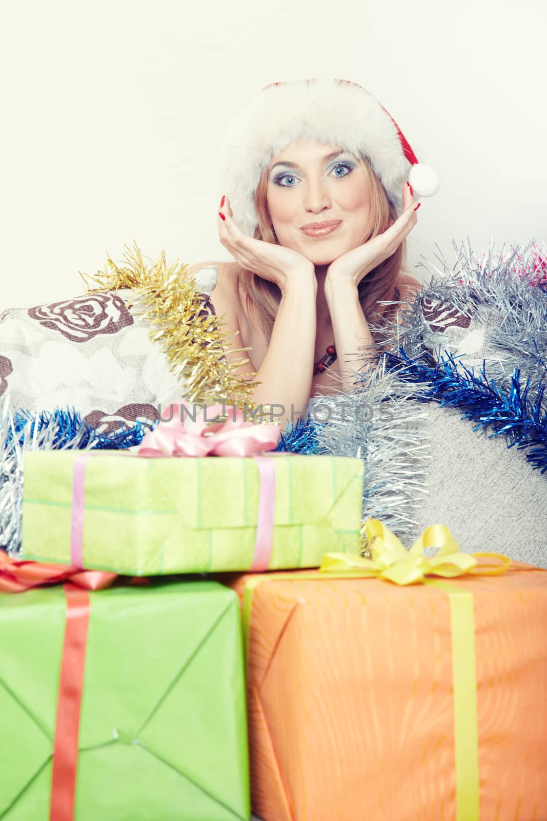 Smiling lady indoors with Santa Claus hat near gift boxes