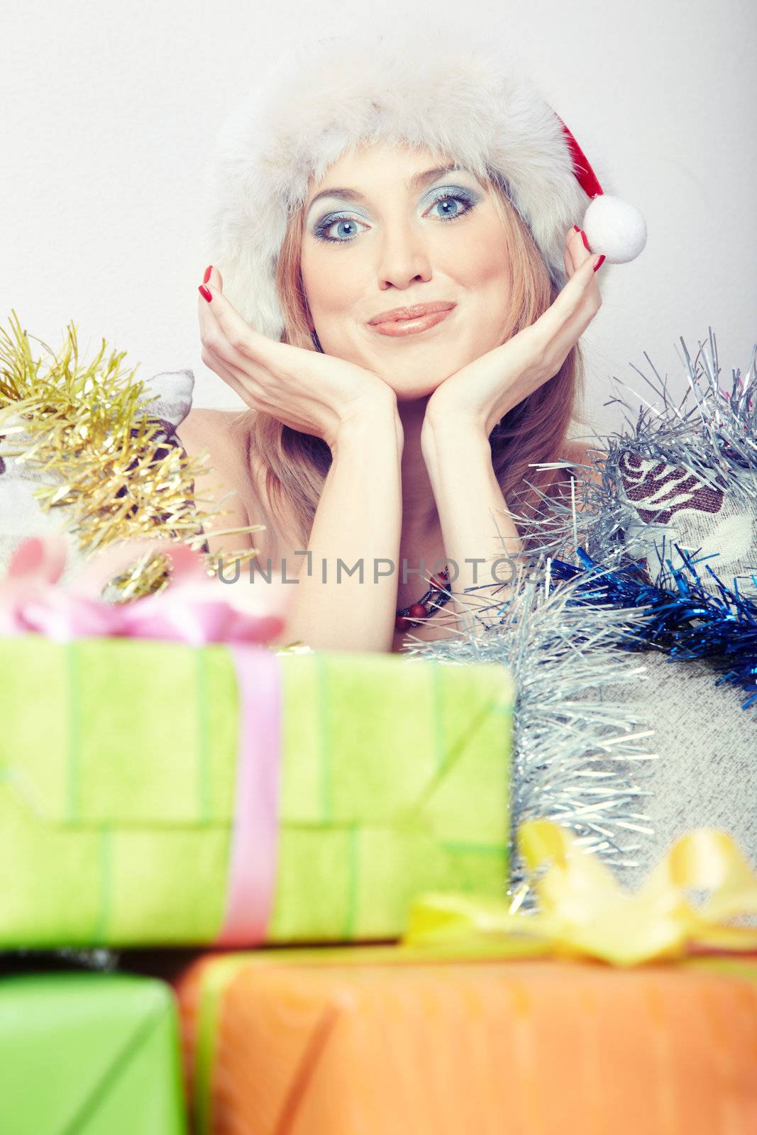 Headshot of the smiling lady in Santa Claus hat behind the boxes with Christmas gifts