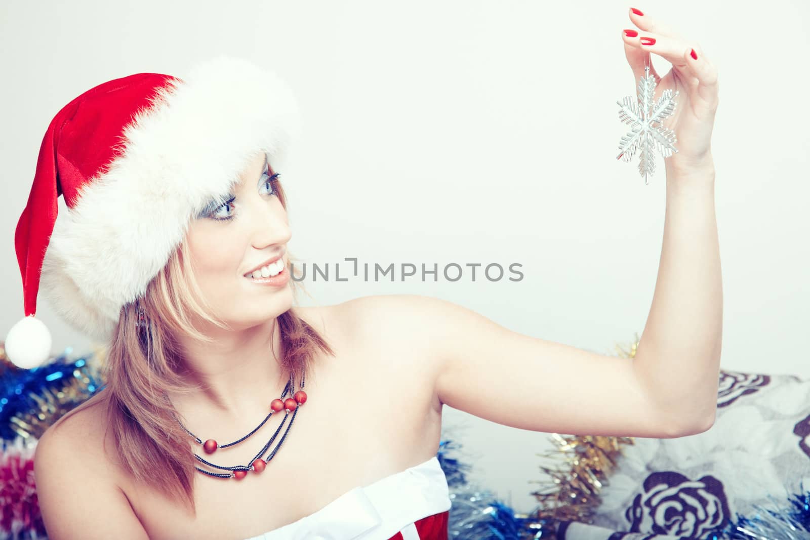 Smiling lady indoors with Santa Claus hat holding Christmas toy. Natural colors and light