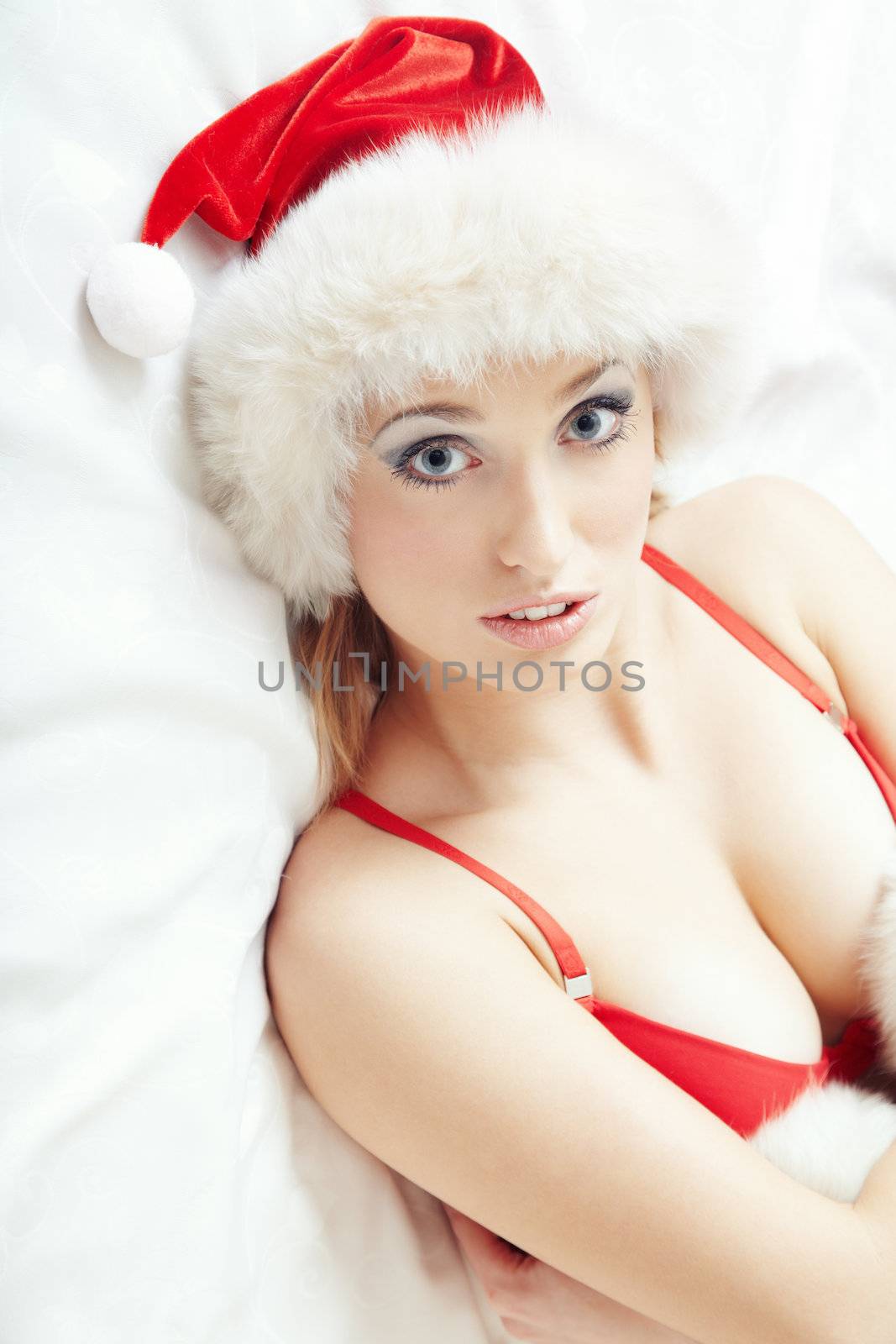 Attractive lady in the red camisole and furry Santa Claus hat laying indoors