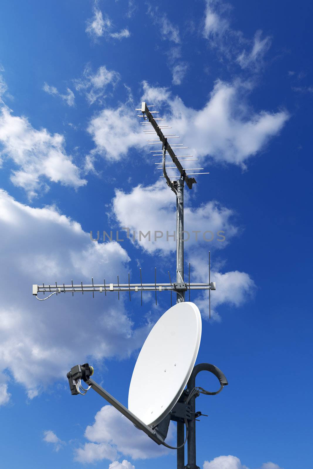 One satellite dish and two TV antennas with a beautiful blue sky