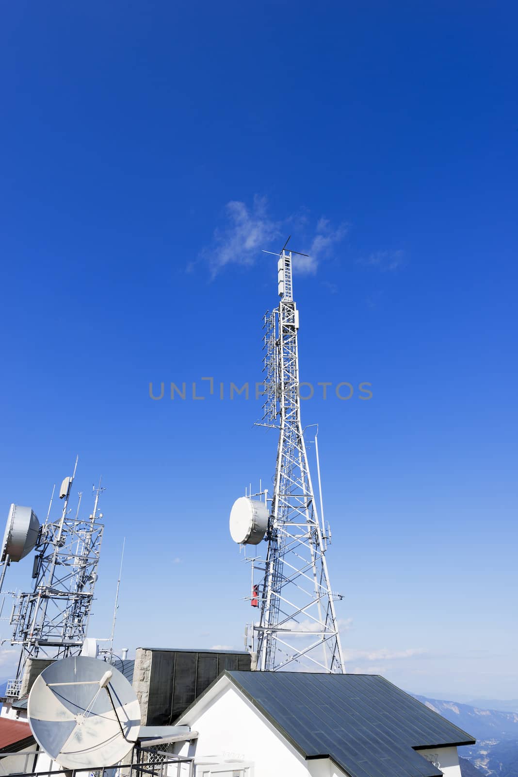 Two communication towers on the roof with a beautiful blue sky