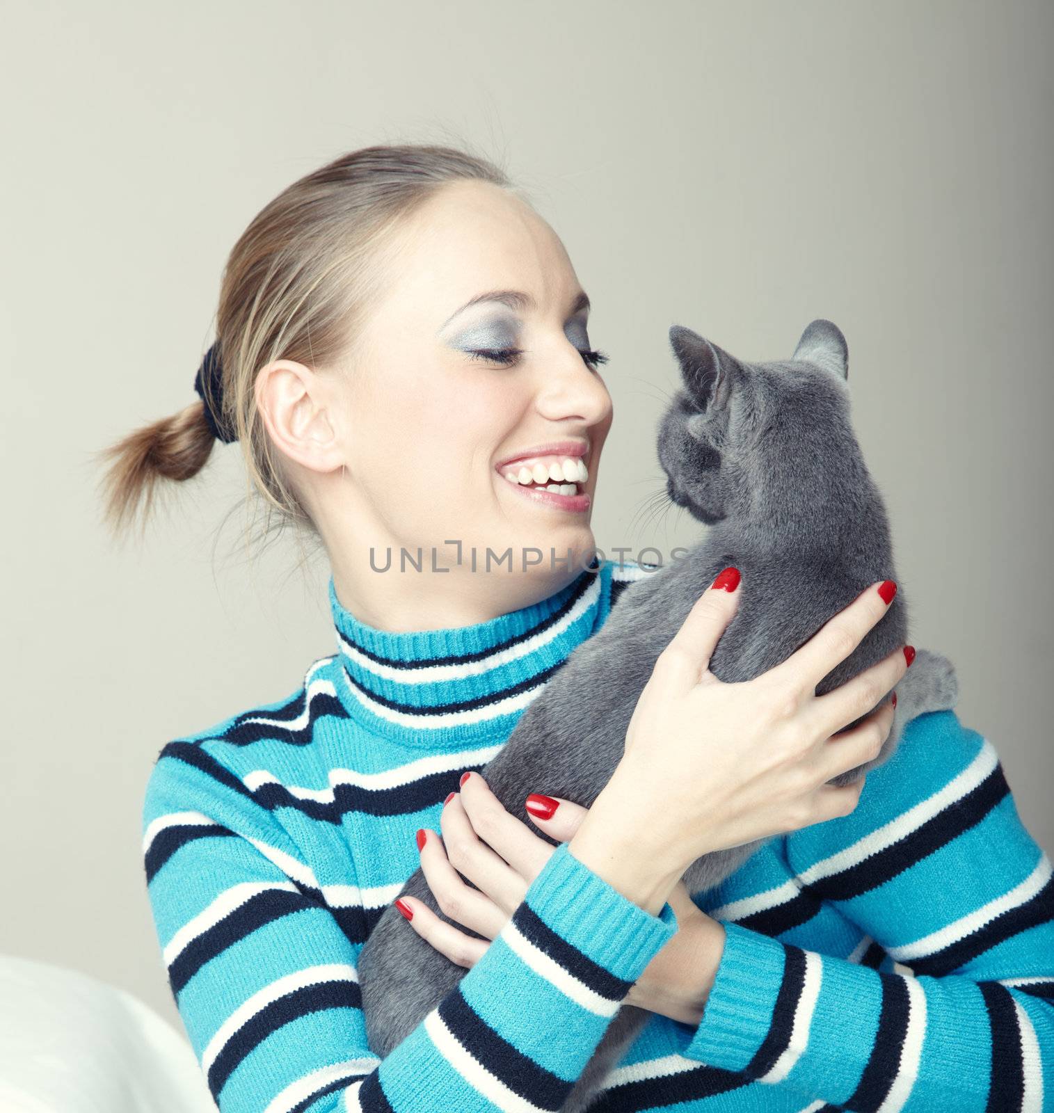 Smiling lady plays with cat indoors