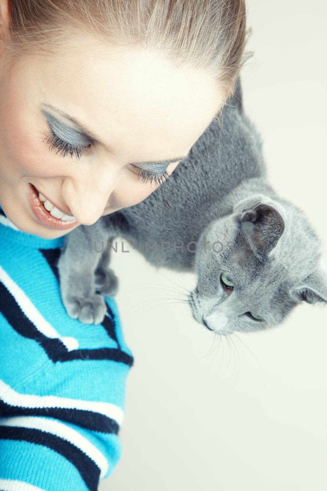 Smiling lady pampering her cat indoors. Natural light and colors