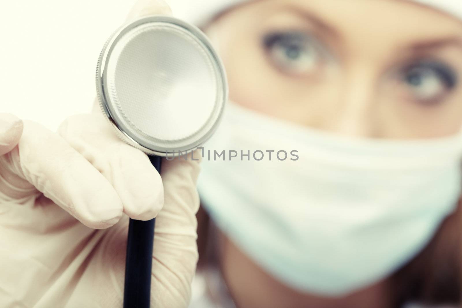 Doctor in protective mask and gloves holding stethoscope. Close-up photo with focus on stethoscope. Shallow depth of field for natural view