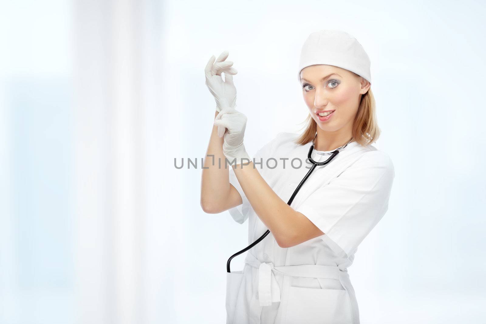Pretty female doctor putting on the latex gloves at hospital