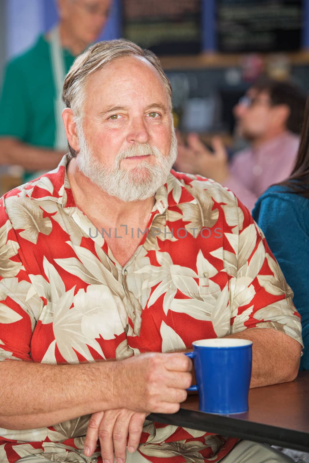 Grinning mature man sitting in cafe with coffee