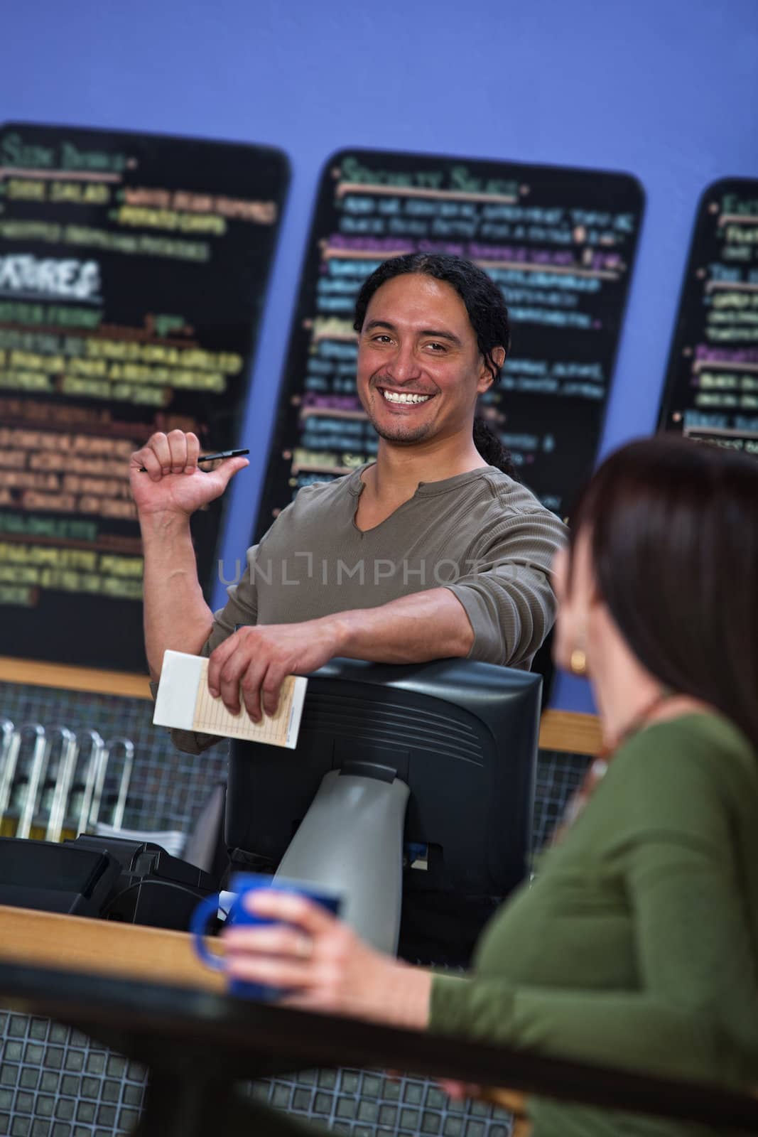 Handsome cafe owner showing menu board to female customer