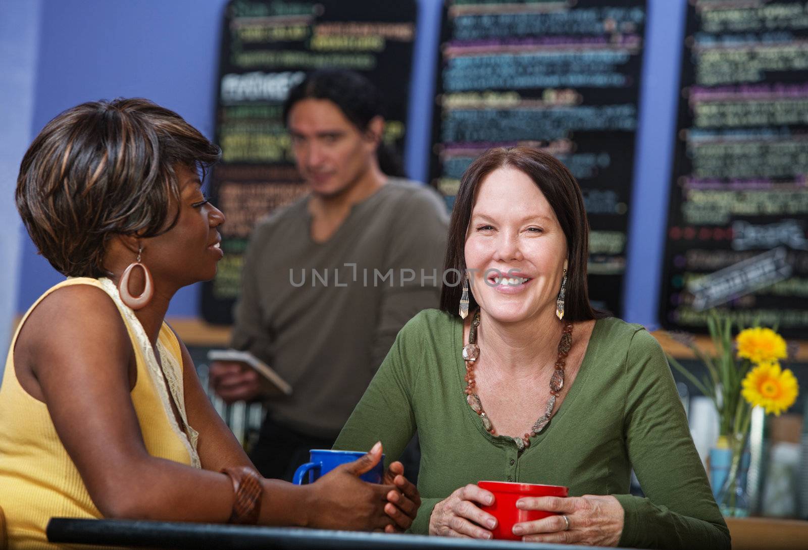 Two happy cafe female customers sitting together