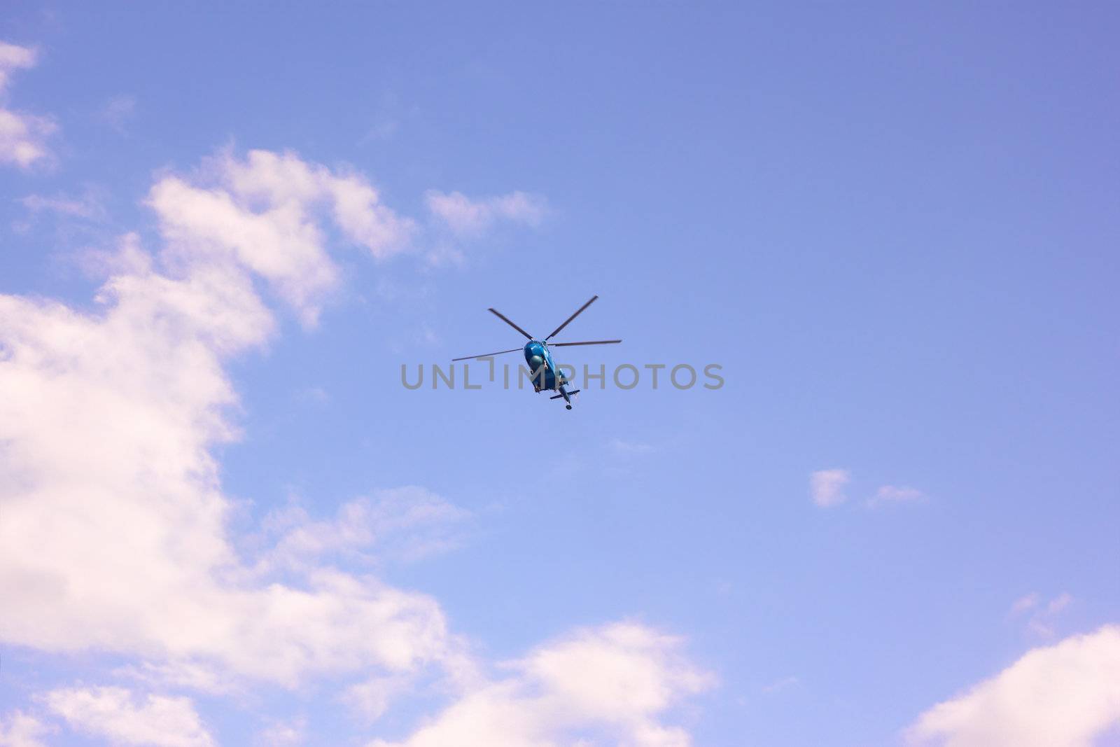 Helicopter flying against the background a blue sky with white clouds
