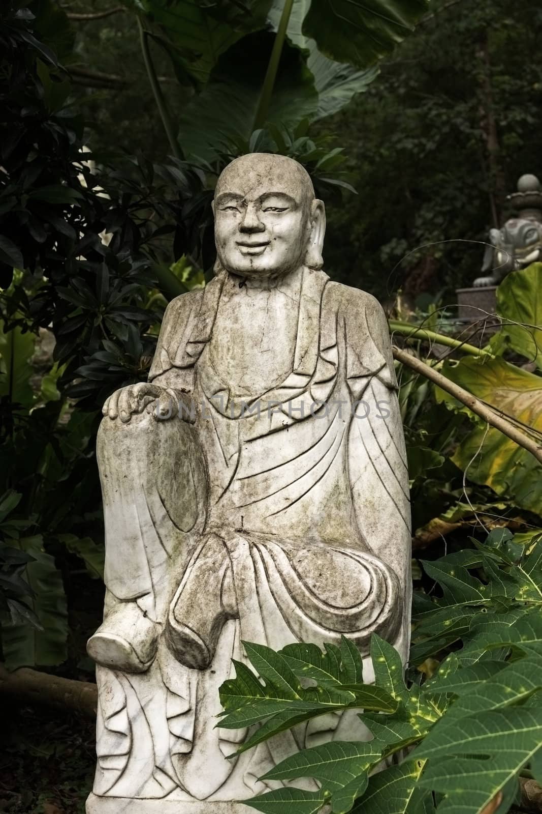 Ruined stone statue Ksitigarbha Bodhisattva in garden.