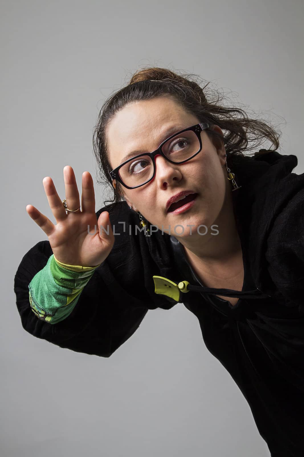 thirtie something brunette woman with glasses cupping her hand to her ear