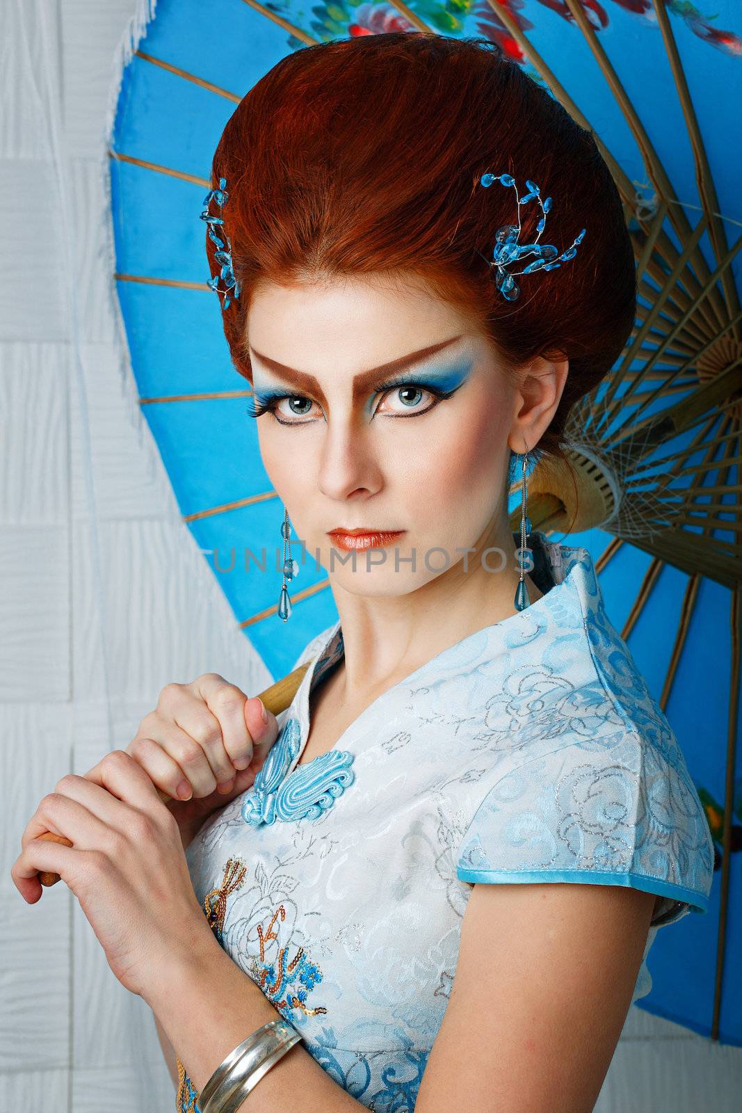 Attractive geisha in a smart dress with an umbrella, photographed in the studio