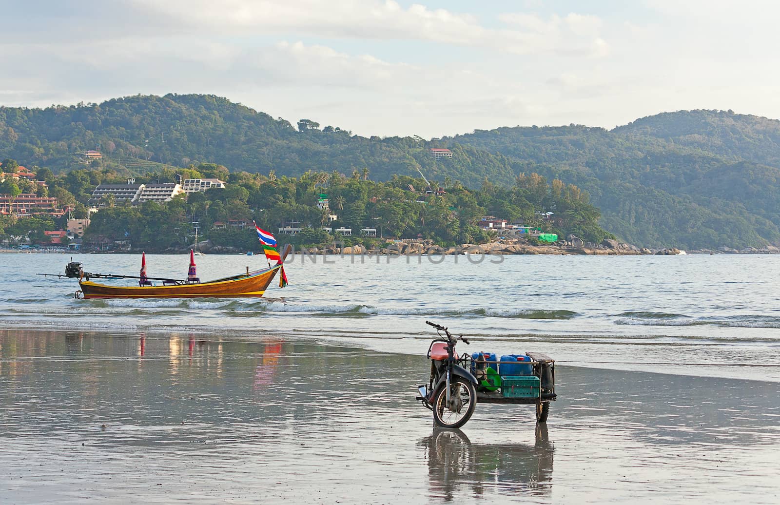 Boat and motorcycle on  seashore against  blue sky, Thailand.