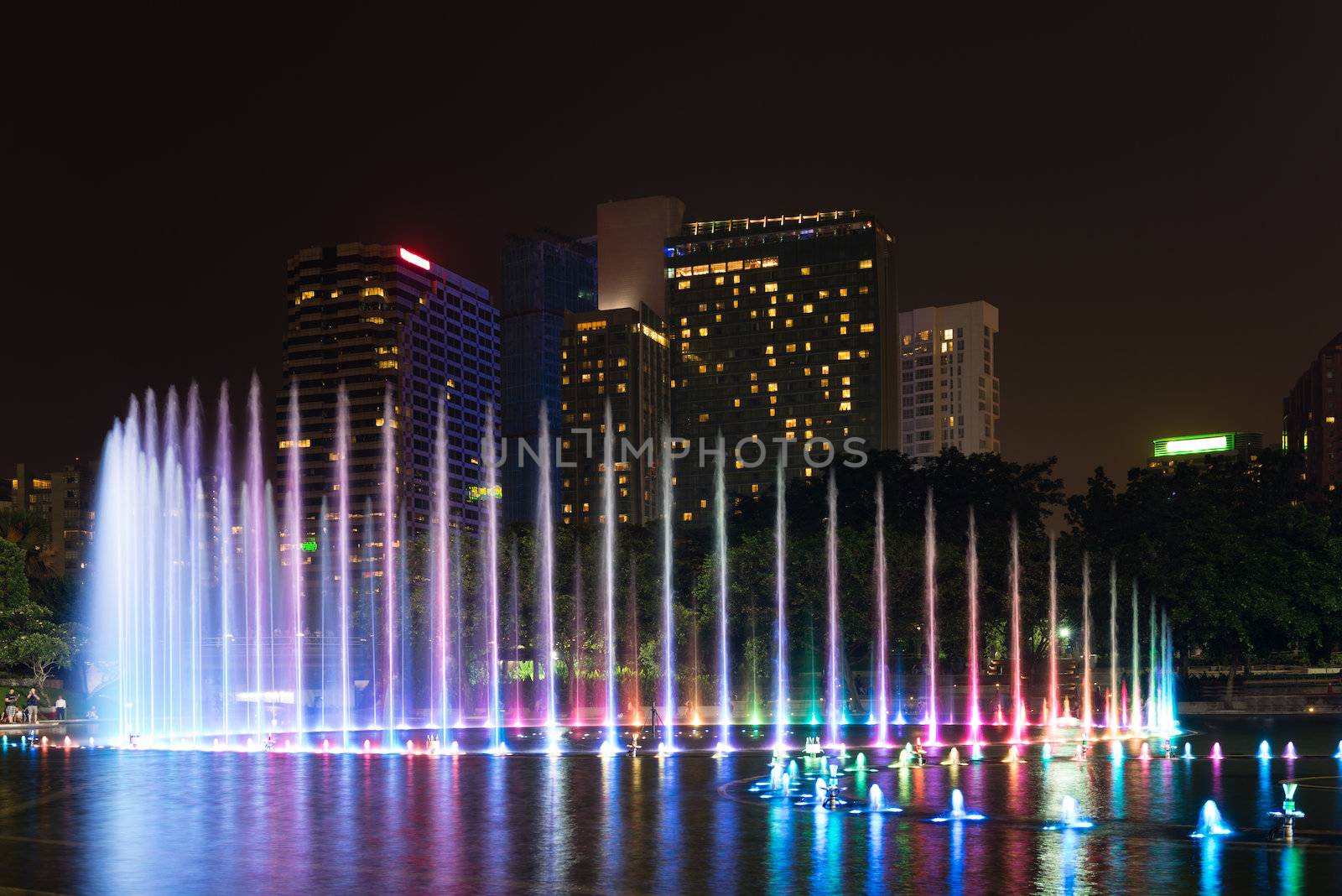 Illuminated fountain at night in modern city skyline, Kuala Lumpur 