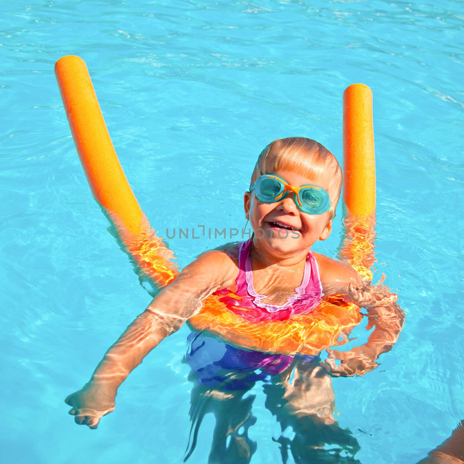 Little girl wearing swimming goggles in a hotel pool