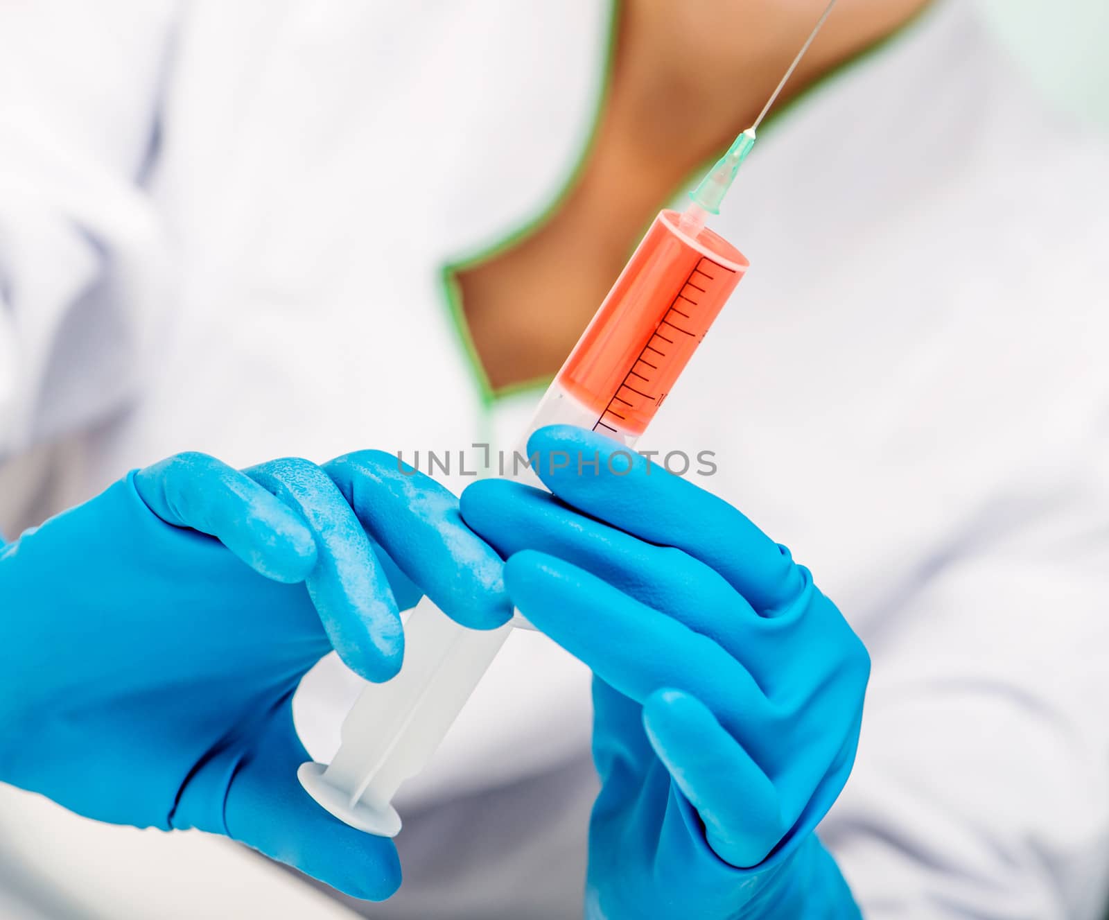 Doctor in blue gloves holding a syringe