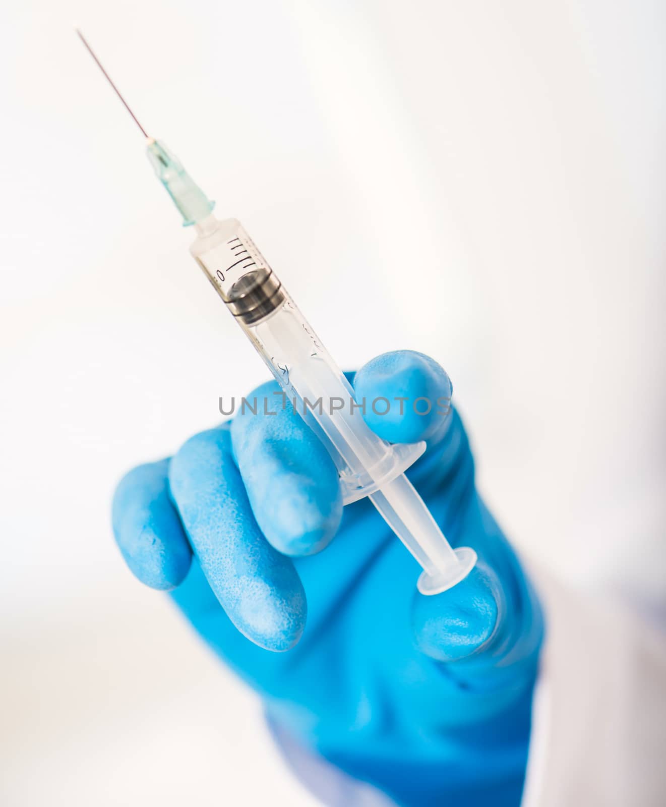 Doctor in blue gloves holding a syringe