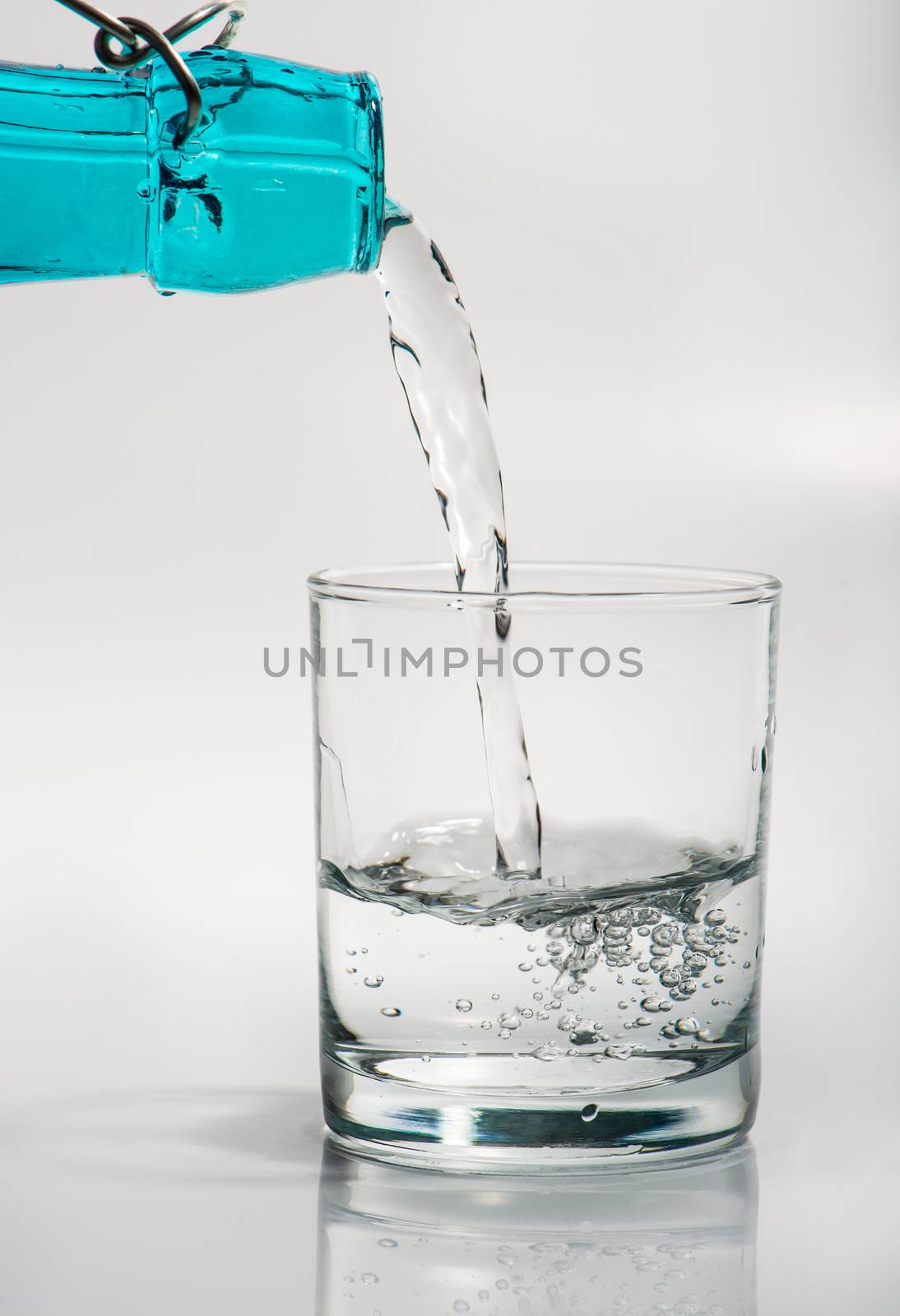 Glass with water pouring from a bottle