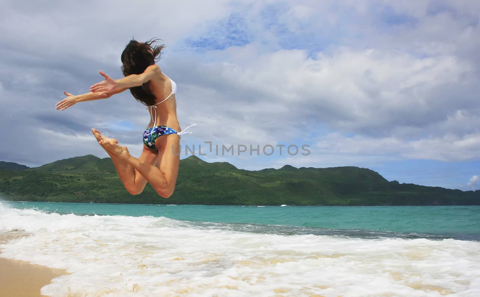 Young woman in bikini jumping at Rincon beach, Samana peninsula, Dominican Republic