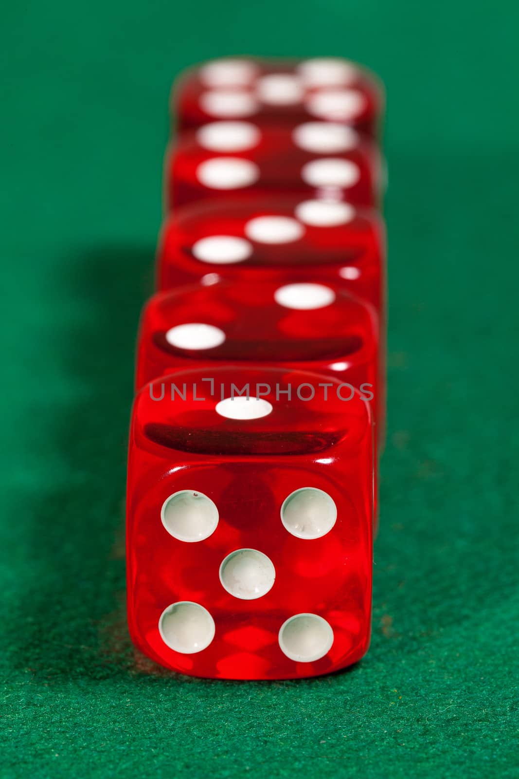 Red dice on green background, closeup