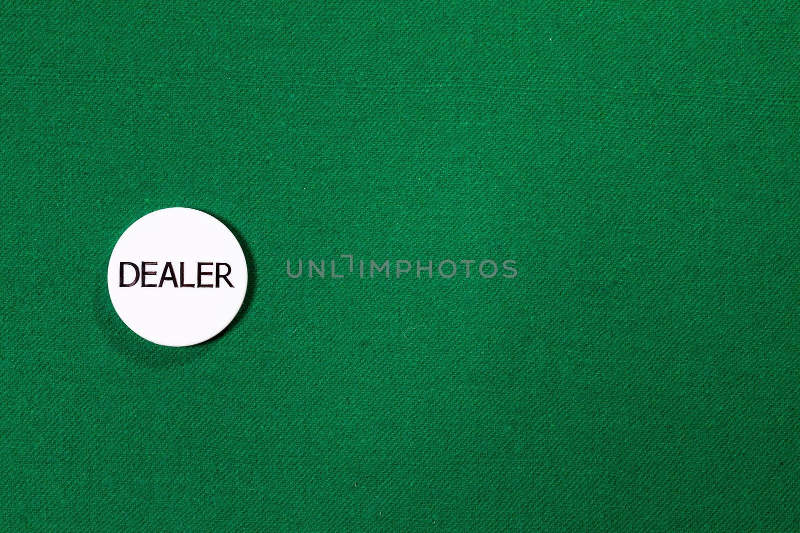 Poker dealer chip on green cloth
