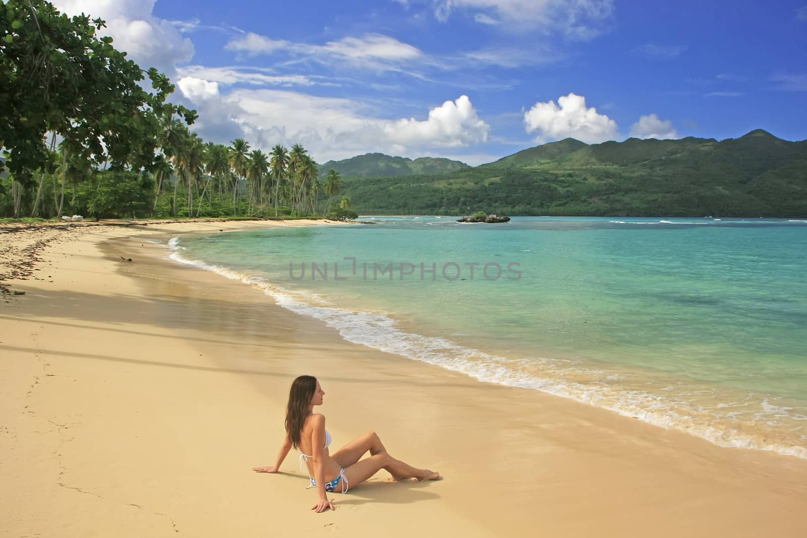 Young woman in bikini sitting at Rincon beach, Samana peninsula, Dominican Republic