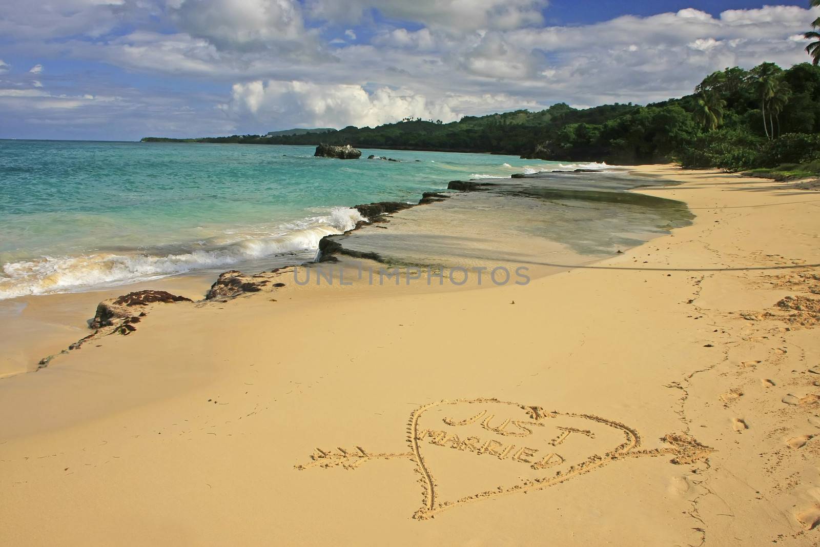 "Just married" written in sand on a beach