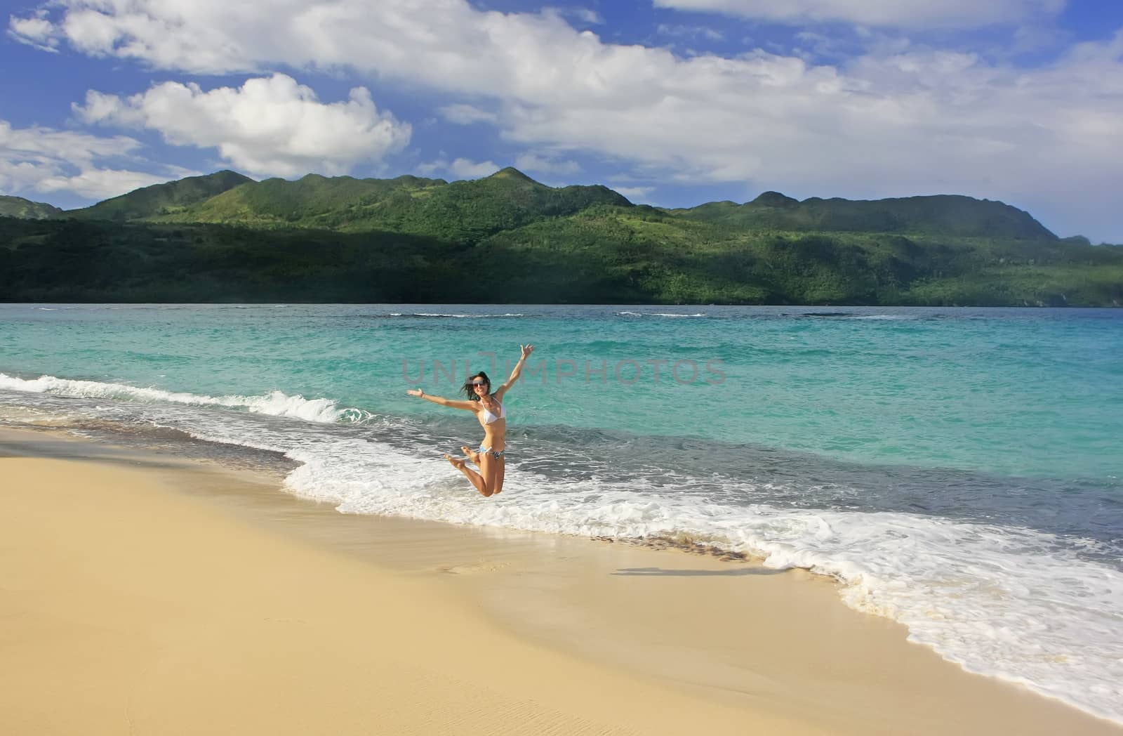 Young woman in bikini jumping at Rincon beach, Samana peninsula, Dominican Republic