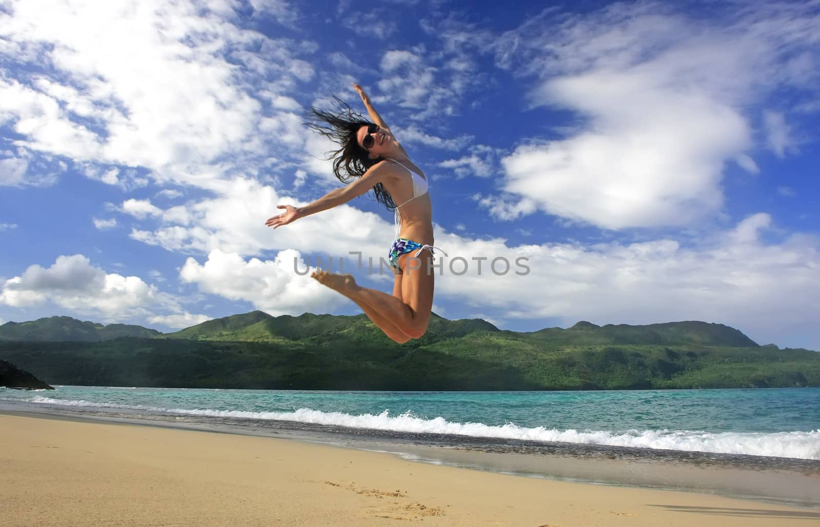 Young woman in bikini jumping at Rincon beach, Samana peninsula, Dominican Republic