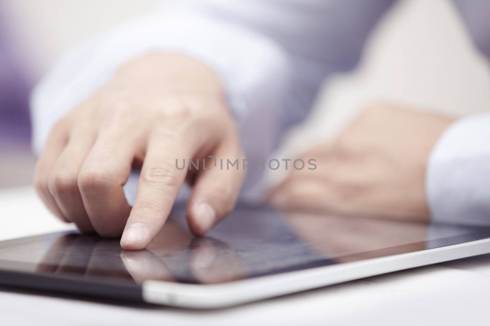 Hands of businessman using tablet PC at office