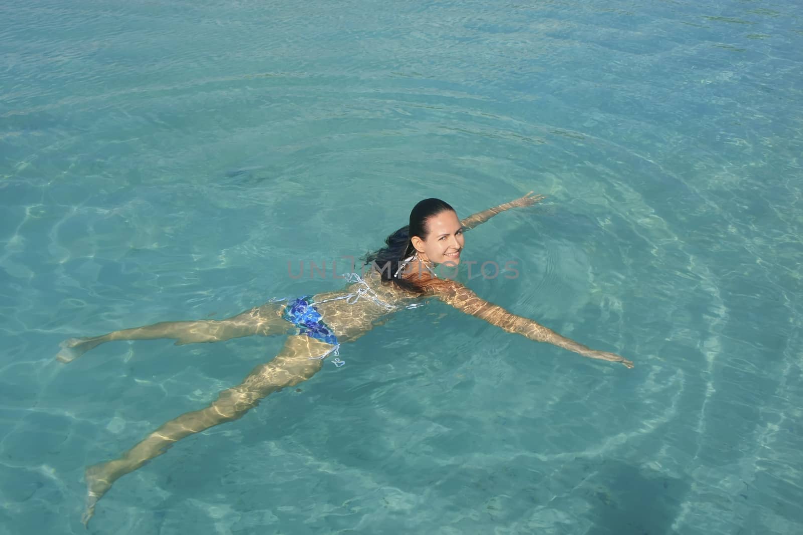 Young woman in bikini swimming in clear water