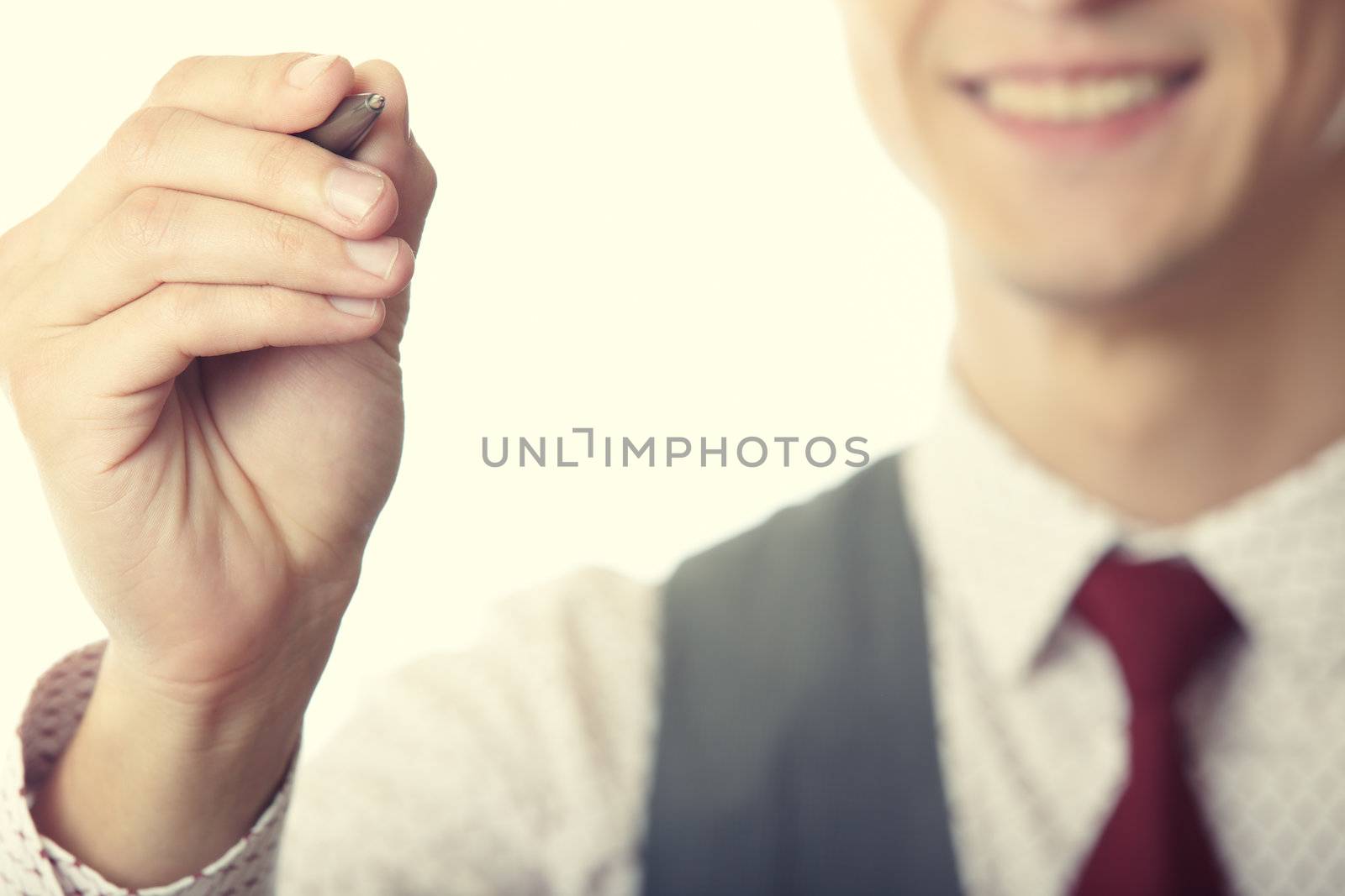 Young smiling businessman is writing on a virtual whiteboard. Focus is on the hand and pen