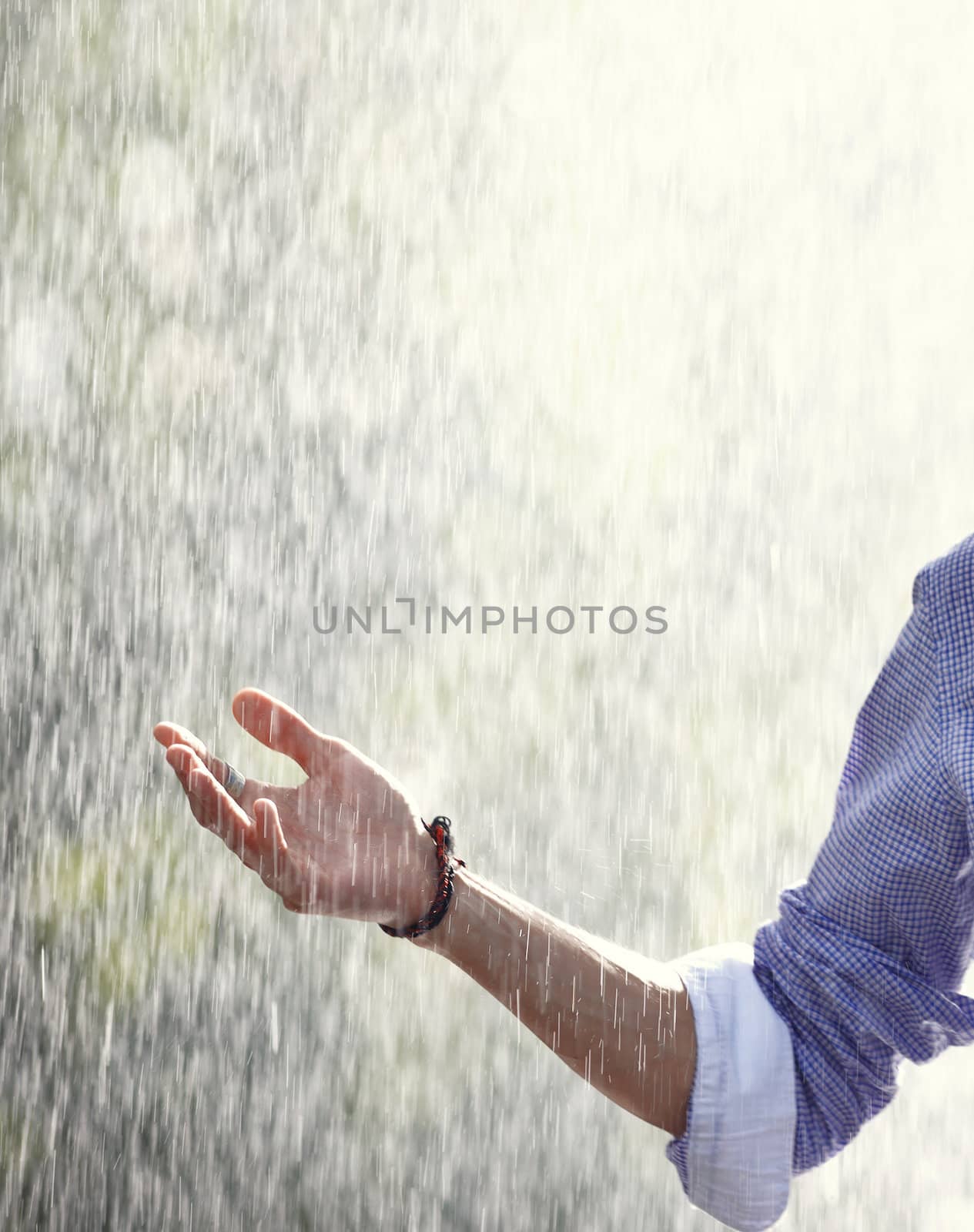 Human hand under the spring or summer rain