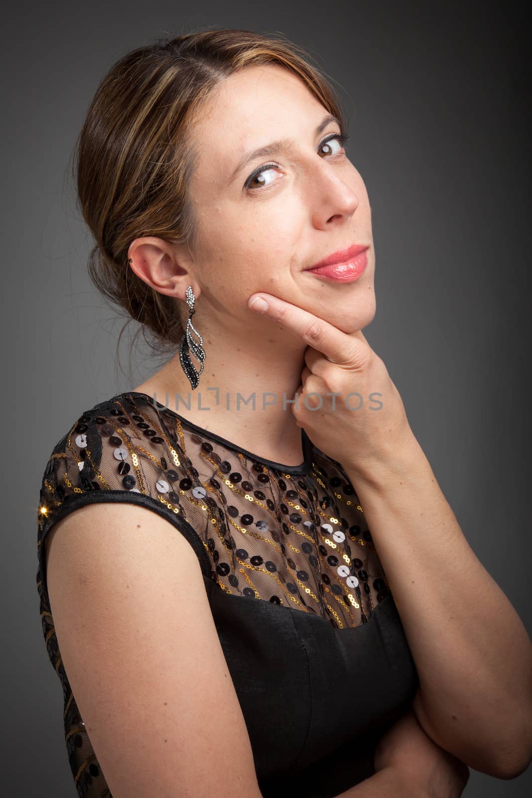 Attractive caucasion girl wearing an evening gown in her 30s shot in studio isolated on a grey background