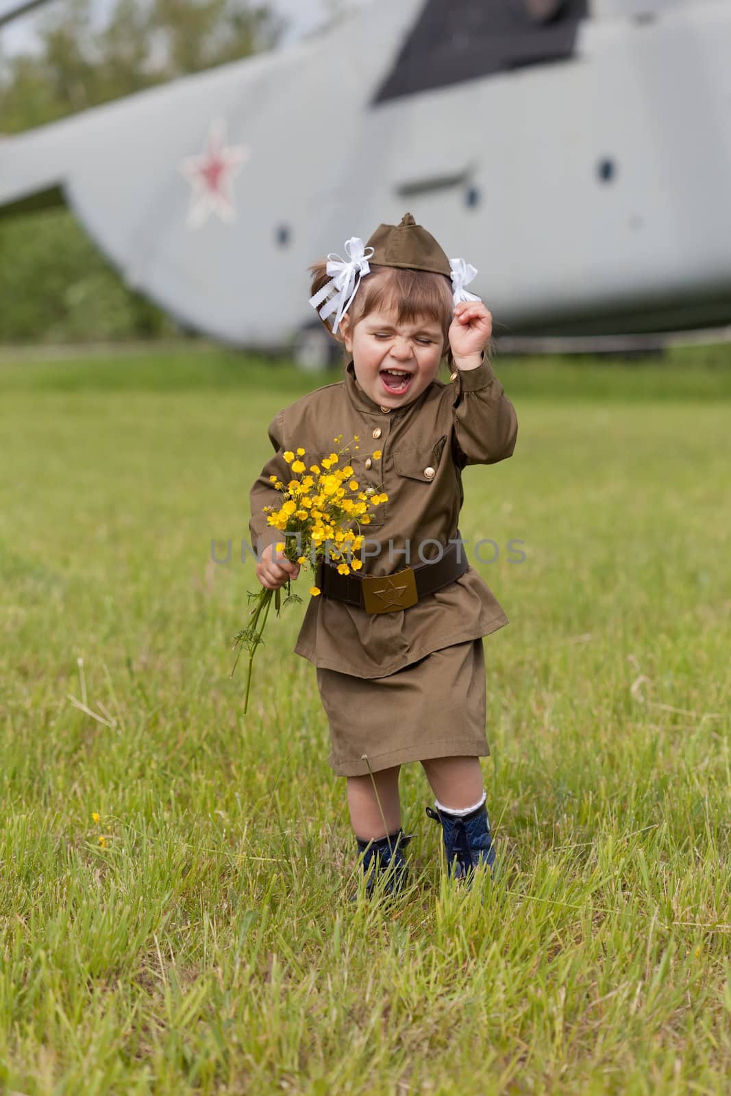 Little girl in a military uniform against planes