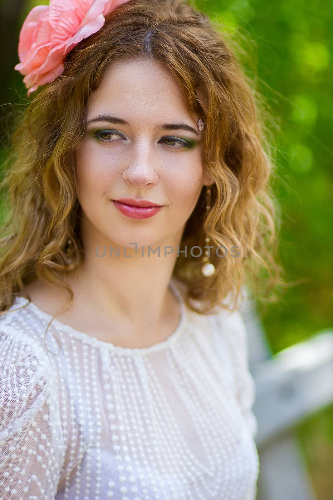 Portrait of a beautiful young woman with curly hair in a smart suit on nature
