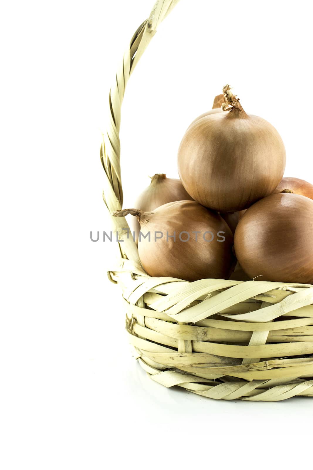 Ripe golden onionsin basket on white background.