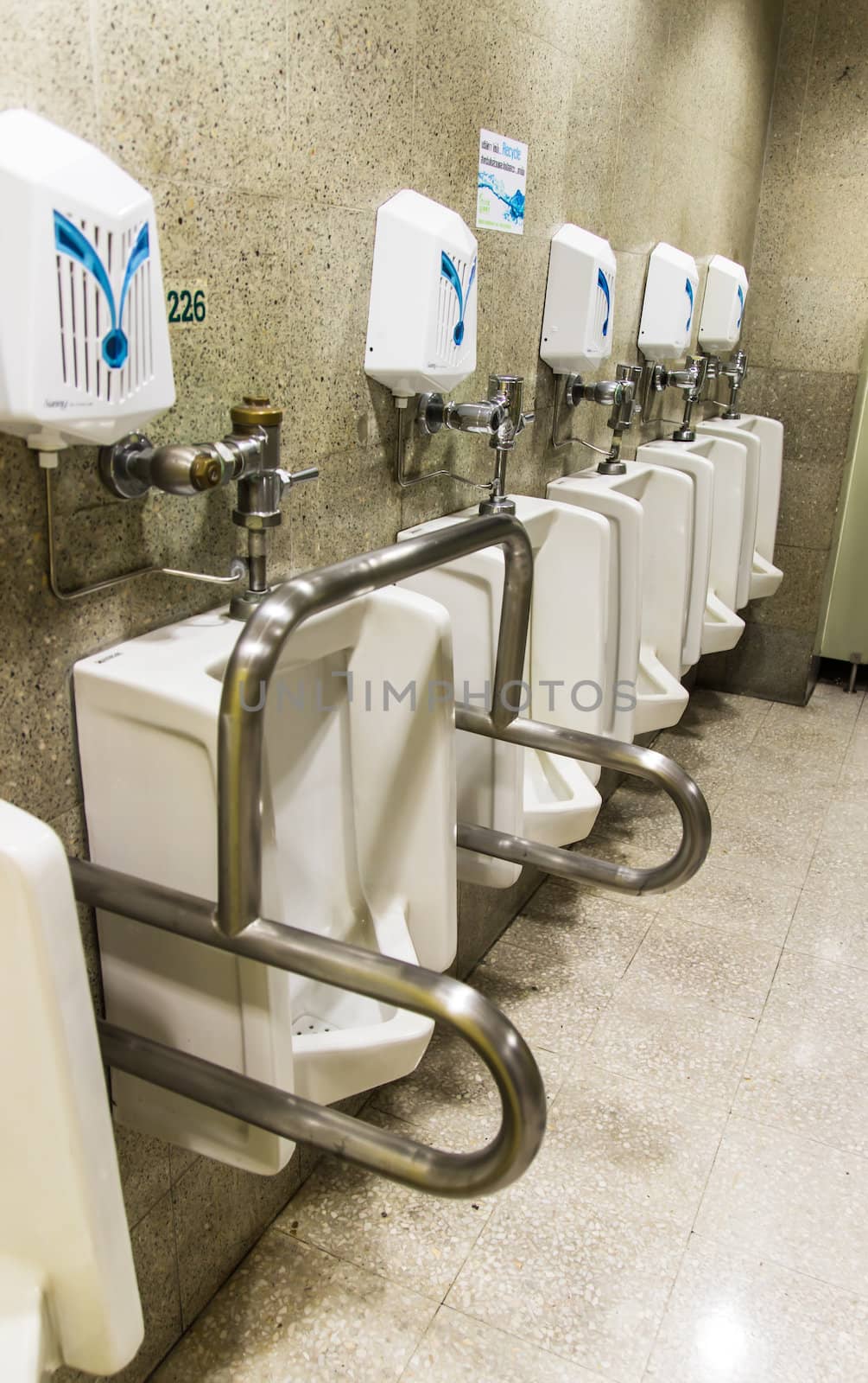 Urinals ,A collection of 5 urinals in a men's bathroom with the one on the left for disabled urinals.